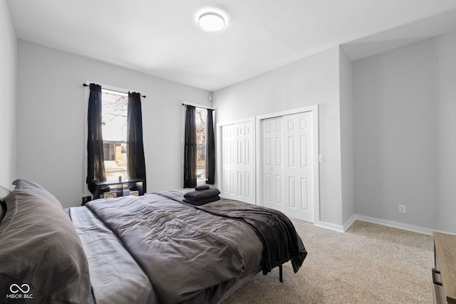 carpeted bedroom with two closets and baseboards