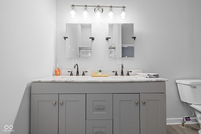 full bath with double vanity, toilet, baseboards, and a sink