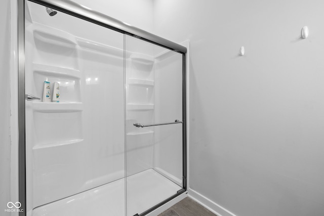 bathroom featuring baseboards, wood finished floors, and a shower stall