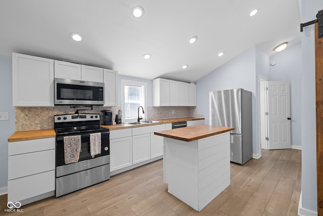 kitchen featuring a sink, butcher block countertops, appliances with stainless steel finishes, and white cabinetry