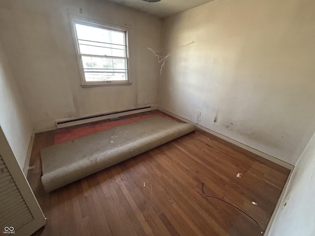 empty room with a baseboard heating unit and wood-type flooring