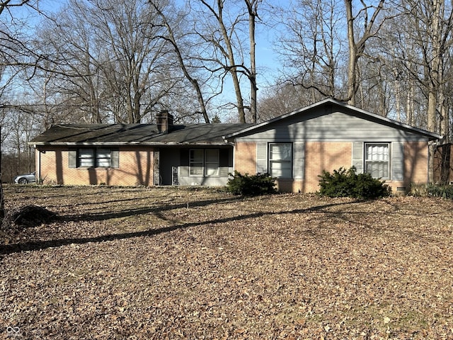 view of front of home featuring brick siding and a chimney