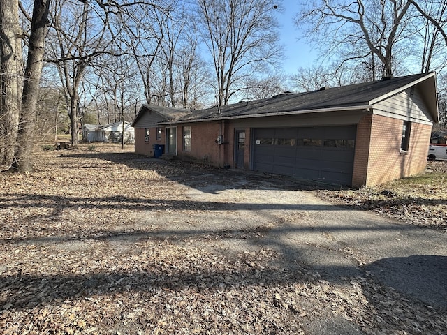 view of home's exterior with a garage, brick siding, and driveway