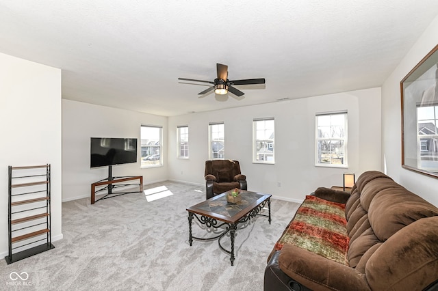 living room with light carpet, a textured ceiling, a ceiling fan, and baseboards