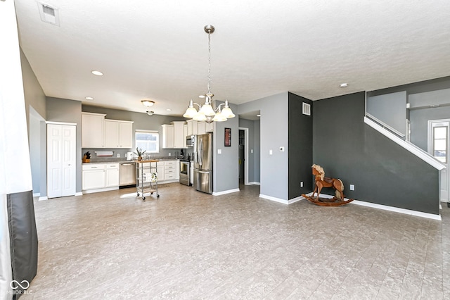 kitchen featuring open floor plan, white cabinets, baseboards, and appliances with stainless steel finishes