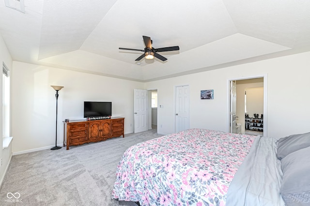 bedroom with a raised ceiling, light colored carpet, visible vents, and baseboards