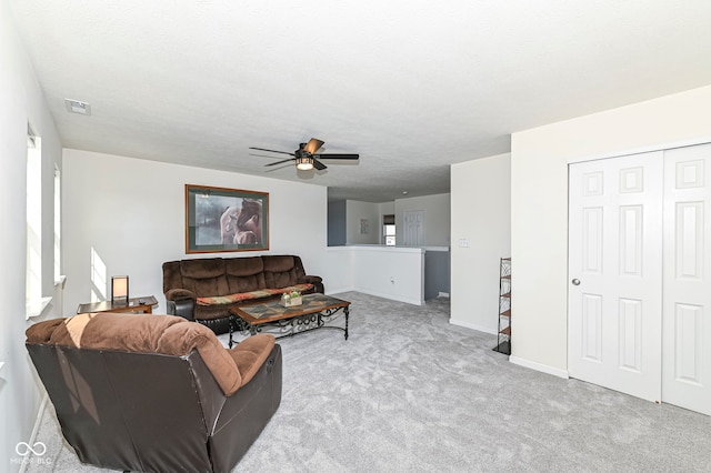carpeted living area featuring visible vents, baseboards, a textured ceiling, and ceiling fan