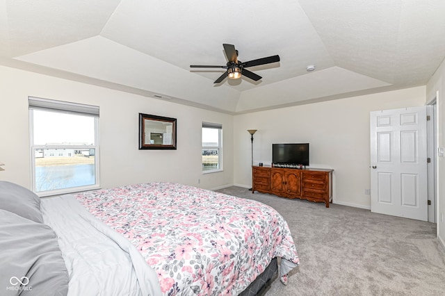 bedroom with visible vents, light colored carpet, a raised ceiling, and baseboards