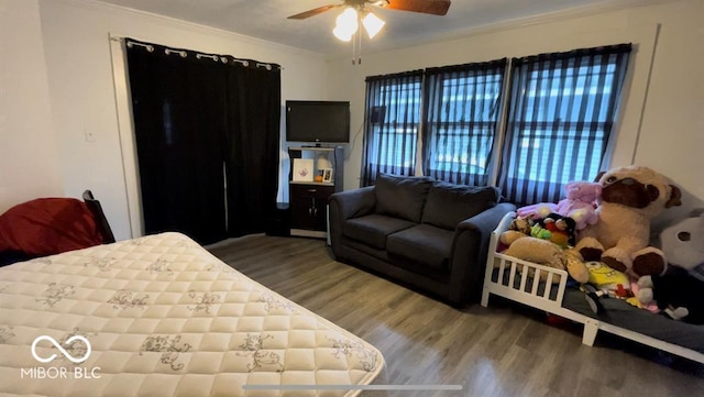 bedroom with ceiling fan, wood finished floors, and ornamental molding