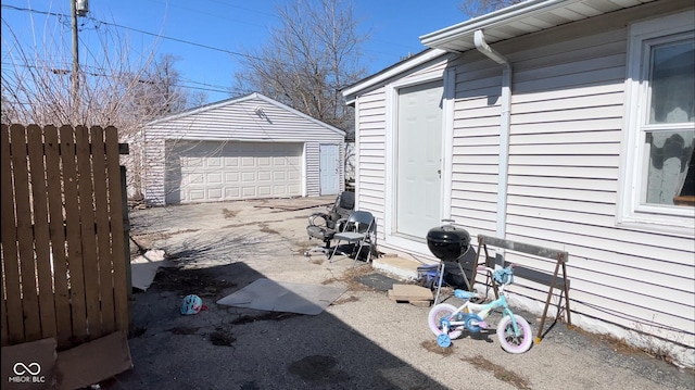 view of patio with a detached garage, an outdoor structure, and fence