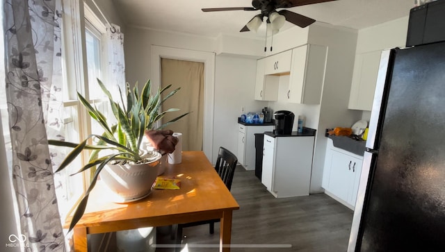 kitchen featuring dark countertops, dark wood finished floors, freestanding refrigerator, white cabinets, and a ceiling fan