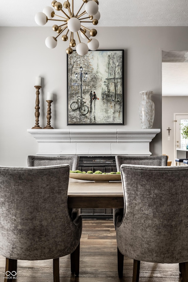 dining area with a notable chandelier, wood finished floors, and a textured ceiling