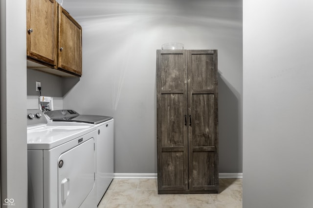 clothes washing area featuring washer and dryer, baseboards, and cabinet space