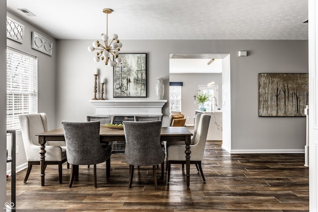 dining space featuring visible vents, baseboards, dark wood finished floors, an inviting chandelier, and a textured ceiling