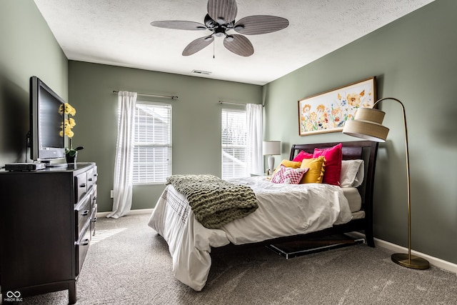 bedroom with visible vents, light colored carpet, a textured ceiling, and baseboards