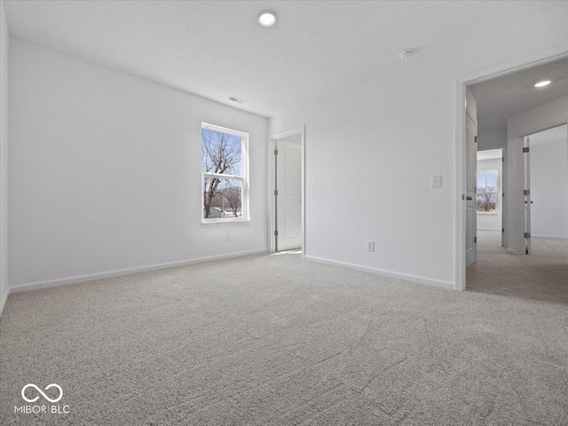 carpeted empty room with recessed lighting, visible vents, and baseboards