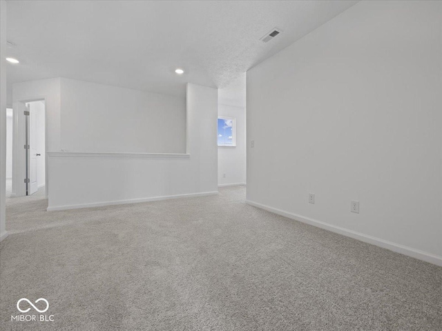 carpeted spare room featuring recessed lighting, baseboards, visible vents, and a textured ceiling