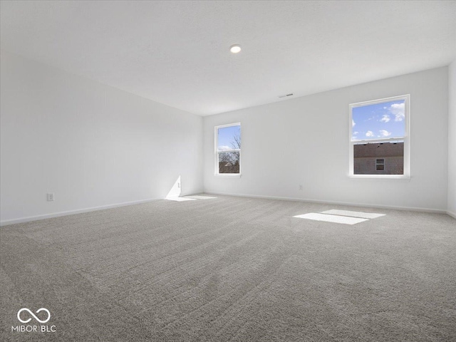 carpeted spare room featuring visible vents and baseboards