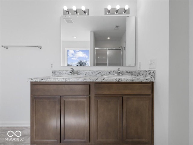 bathroom with a shower stall, double vanity, visible vents, and a sink