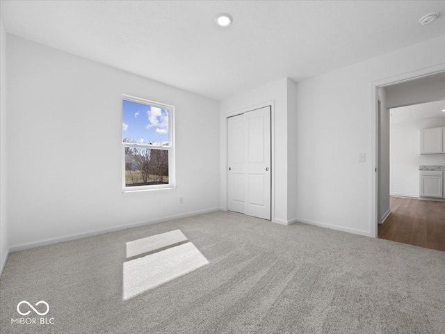 unfurnished bedroom featuring a closet, baseboards, a textured ceiling, and carpet flooring