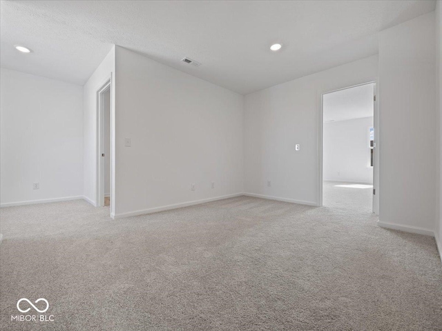 spare room with recessed lighting, visible vents, light carpet, and baseboards