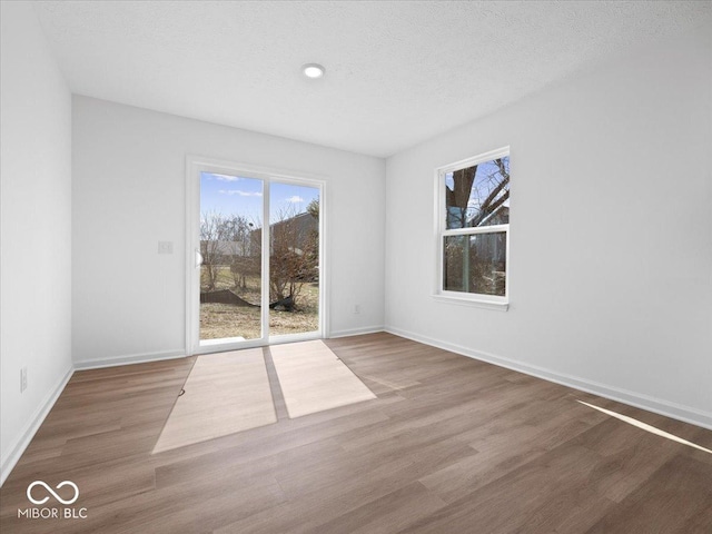 spare room featuring baseboards, a textured ceiling, and wood finished floors