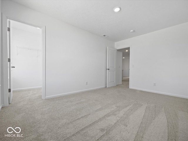 carpeted spare room featuring visible vents, recessed lighting, a textured ceiling, and baseboards