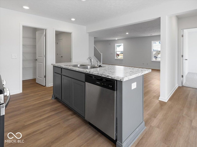 kitchen featuring dishwasher, light countertops, light wood-style floors, a textured ceiling, and a sink