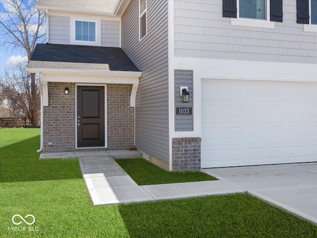 entrance to property with brick siding, an attached garage, a shingled roof, and a yard