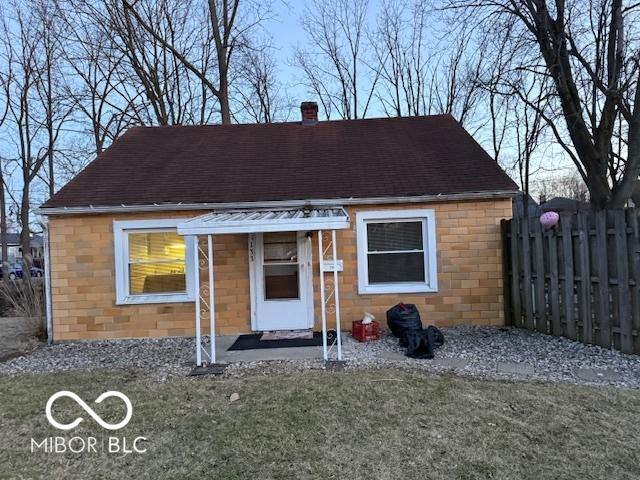 exterior space with a shingled roof, a front lawn, fence, and a chimney