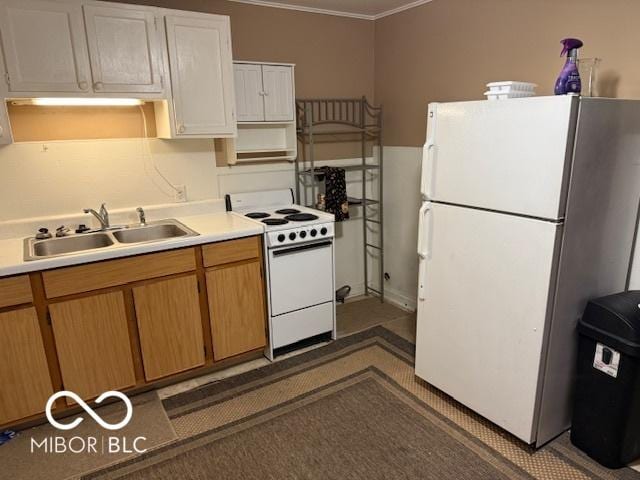 kitchen with a sink, white appliances, ornamental molding, and light countertops