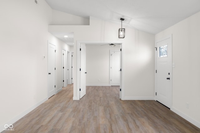 foyer entrance with light wood-type flooring, baseboards, and vaulted ceiling