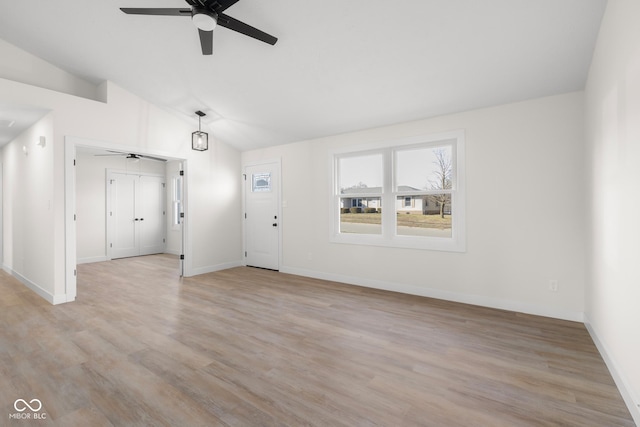 unfurnished living room with vaulted ceiling, a ceiling fan, baseboards, and light wood finished floors