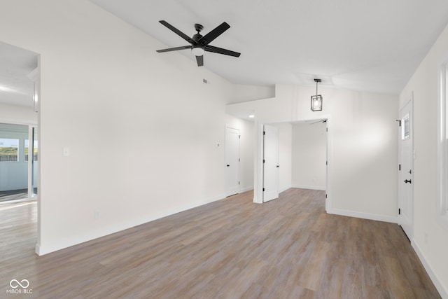 unfurnished living room featuring vaulted ceiling, baseboards, light wood finished floors, and ceiling fan