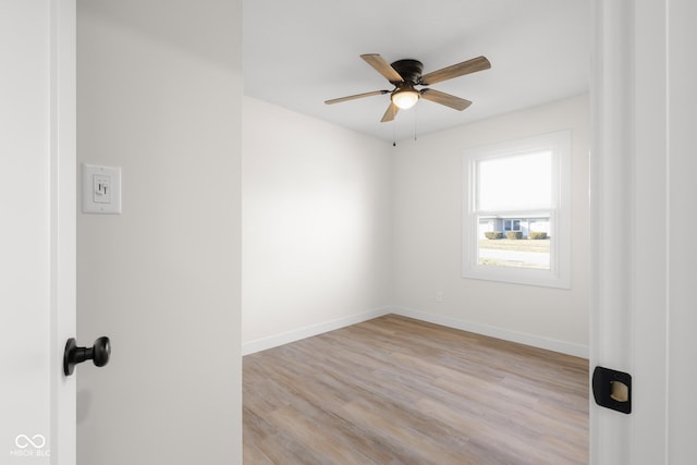 spare room with a ceiling fan, light wood-style floors, and baseboards