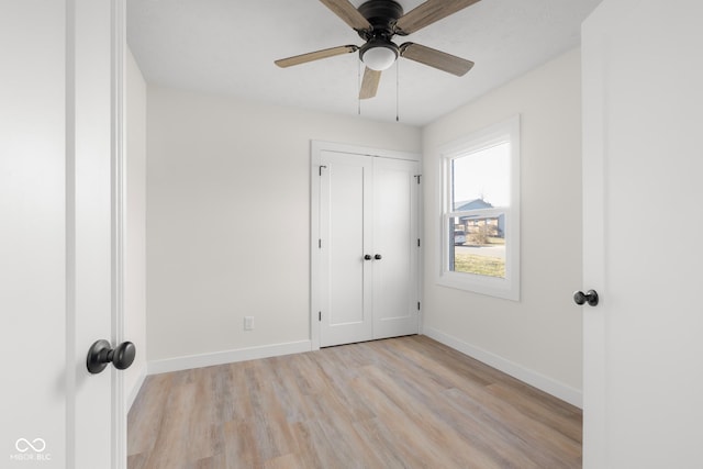 unfurnished bedroom with a closet, baseboards, light wood-style floors, and a ceiling fan