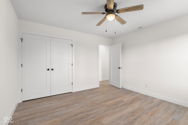 unfurnished bedroom with light wood finished floors, visible vents, ceiling fan, baseboards, and a closet