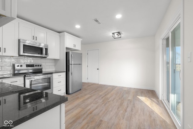 kitchen with light wood-type flooring, visible vents, backsplash, stainless steel appliances, and white cabinets