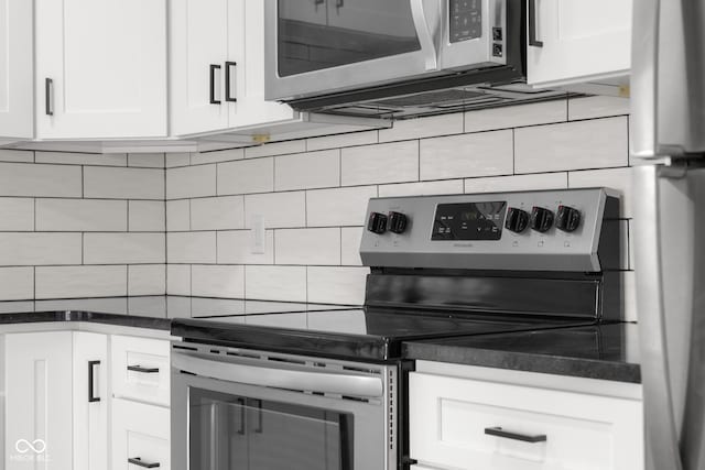 kitchen featuring decorative backsplash, dark countertops, white cabinets, and stainless steel appliances