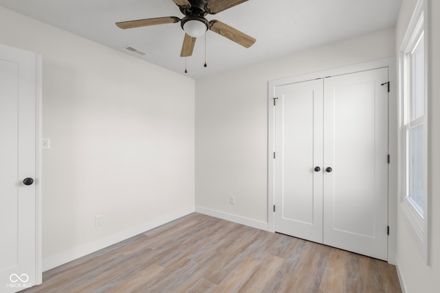 unfurnished bedroom featuring visible vents, a closet, light wood finished floors, baseboards, and ceiling fan