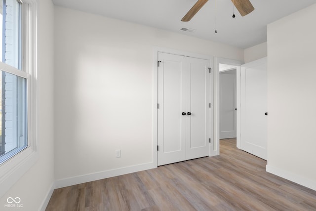 unfurnished bedroom with visible vents, ceiling fan, baseboards, wood finished floors, and a closet