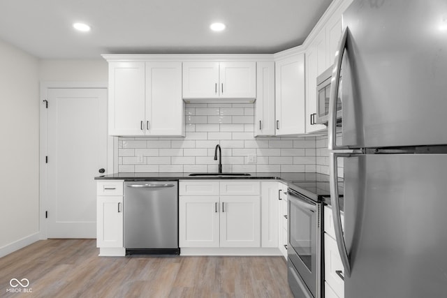 kitchen featuring dark countertops, light wood-style flooring, appliances with stainless steel finishes, and a sink