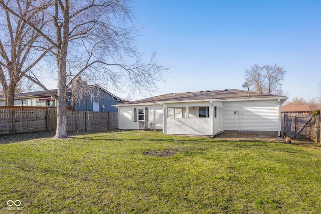 back of house with a yard and a fenced backyard