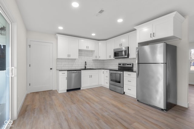 kitchen with dark countertops, light wood-style flooring, visible vents, and stainless steel appliances