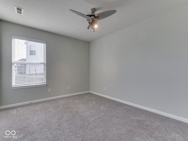 spare room featuring visible vents, a textured ceiling, carpet floors, baseboards, and ceiling fan