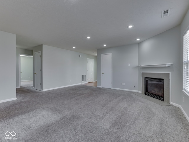 unfurnished living room with visible vents, recessed lighting, carpet flooring, and a fireplace with flush hearth