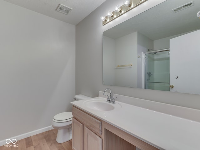 bathroom with a shower with shower door, visible vents, toilet, and wood finished floors