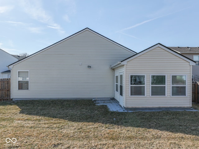 back of property with a lawn and fence