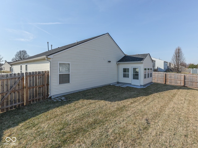 rear view of property with a lawn and a fenced backyard