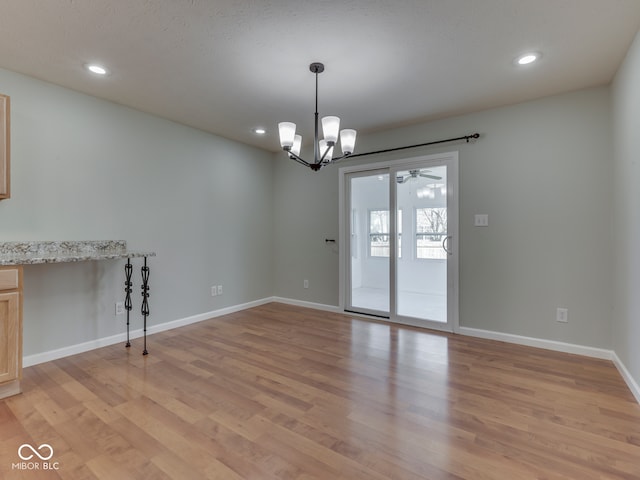 spare room featuring recessed lighting, baseboards, light wood-type flooring, and a chandelier